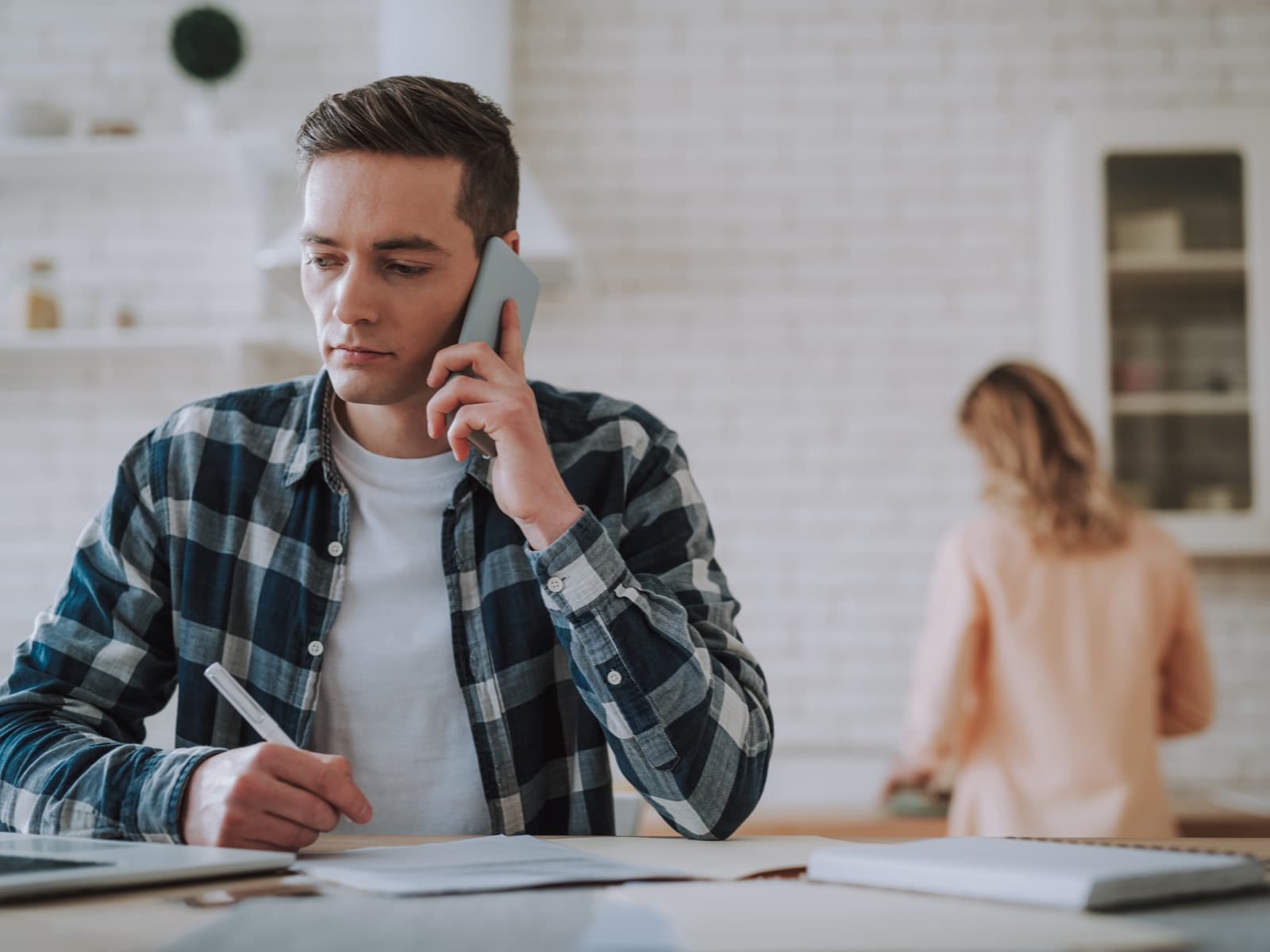 Man working from home on phone and writing.