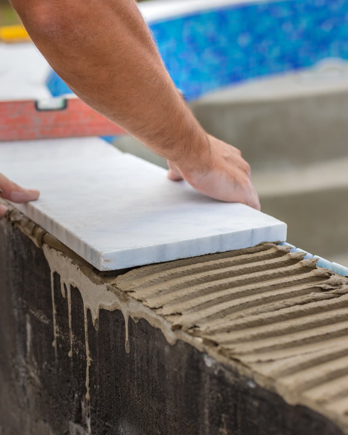 A technician lays tiles in a swimming pool select.
