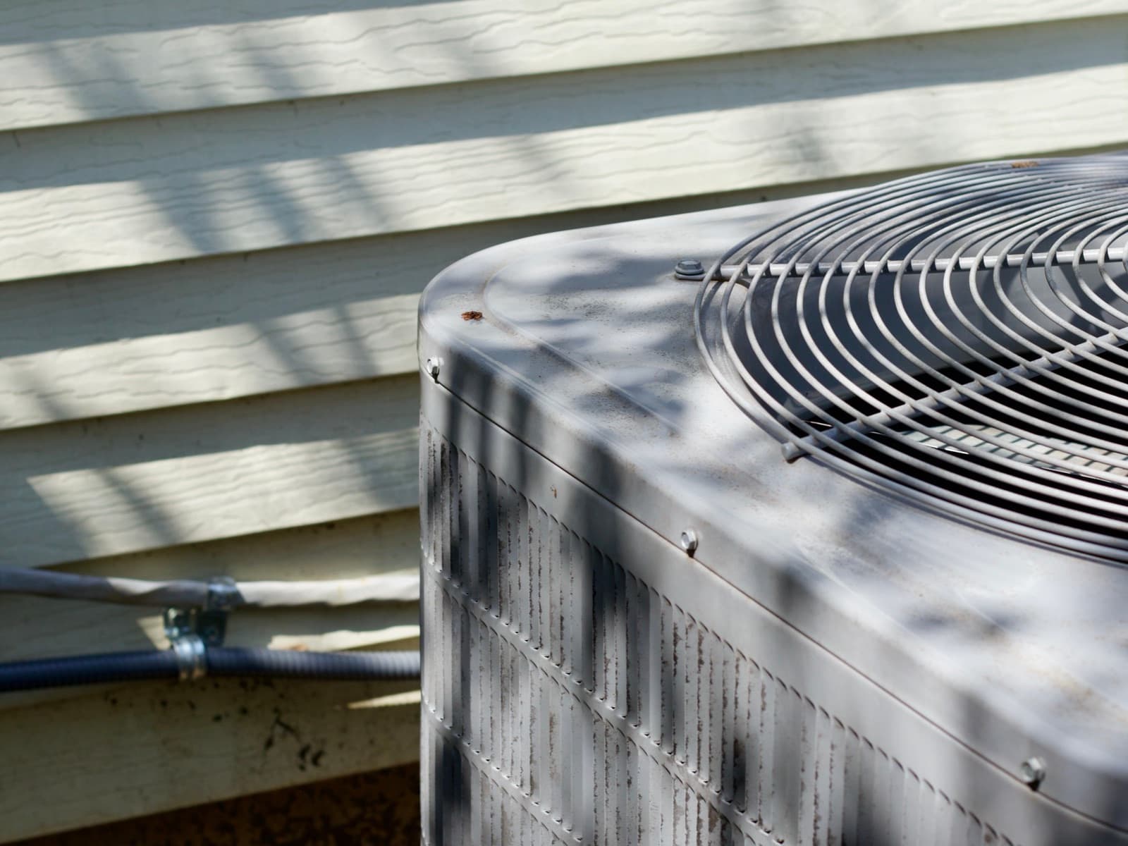 Air conditioner unit outdoors next to house siding.