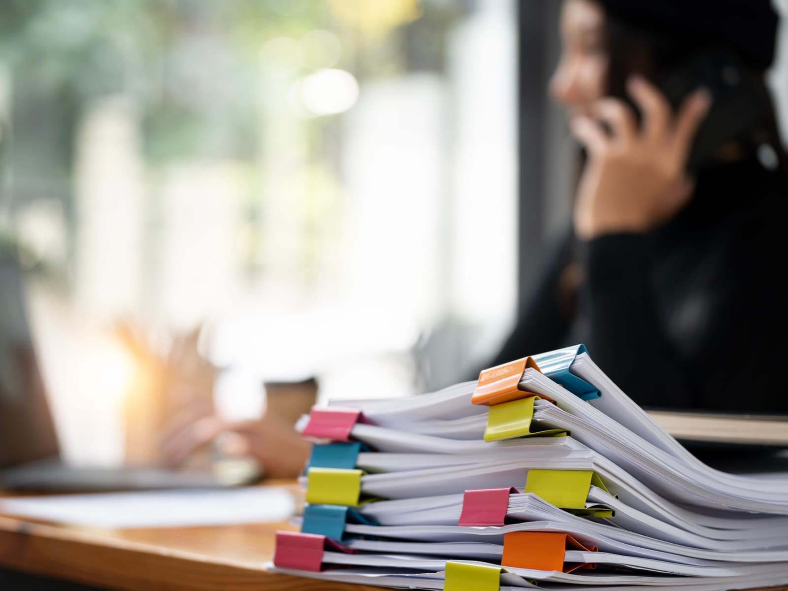 Businesswoman on phone with paperwork in office.