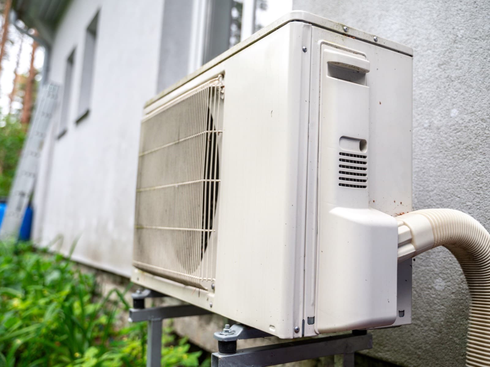 Air conditioning unit outside house with greenery.